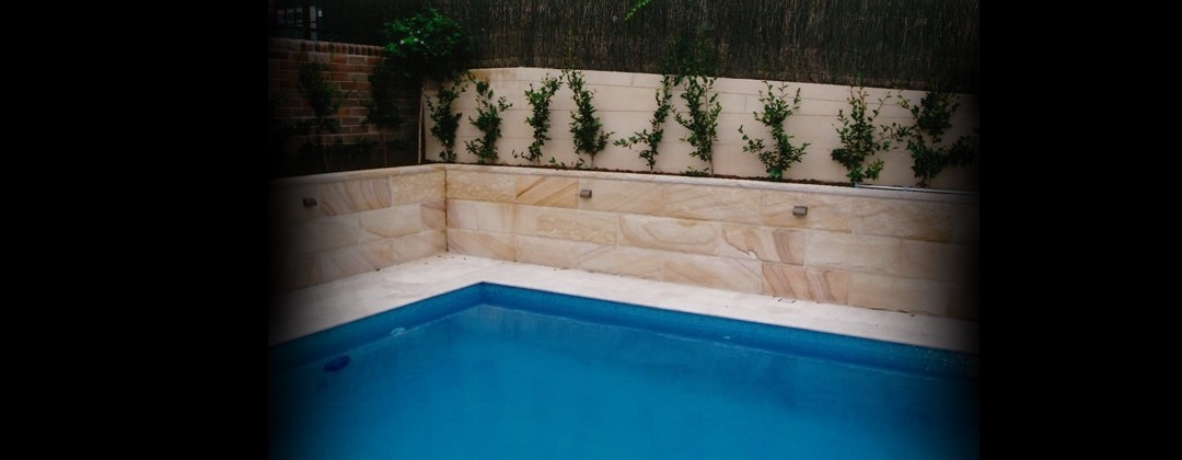 Swimming pool bounded by a sandstone terraced garden