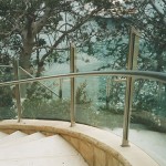 Contemporary stone masonry curved stairway entrance with stainless steel rails located on the harbour marine environment.